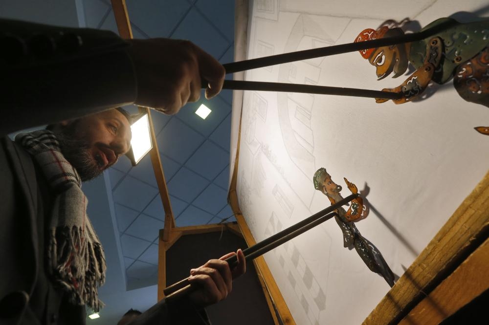 Shadi Al-Hallaq is seen moving his puppets Karakoz and Eiwaz from inside his booth during a presentation in Damascus, this week.