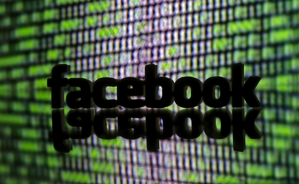 File photo shows a 3D printed Facebook logo is seen in front of displayed cyber code in this illustration. — Reuters