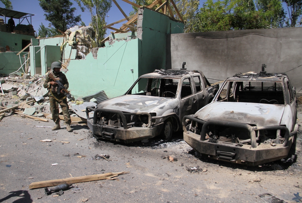 A member of the Afghan security forces stands guard next to damaged army vehicles after a Taliban attack in Ghazni city, Afghanistan, in this file photo. — Reuters
