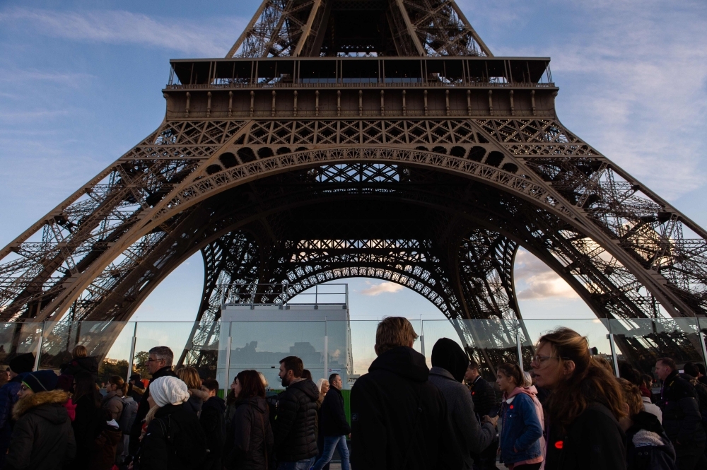In this file photo, people are seen walking along the Eiffel tower in Paris. The Eiffel Tower will be closed on Dec. 8, 2018 amid 'yellow vest' protests planned on the same day in Paris. — AFP