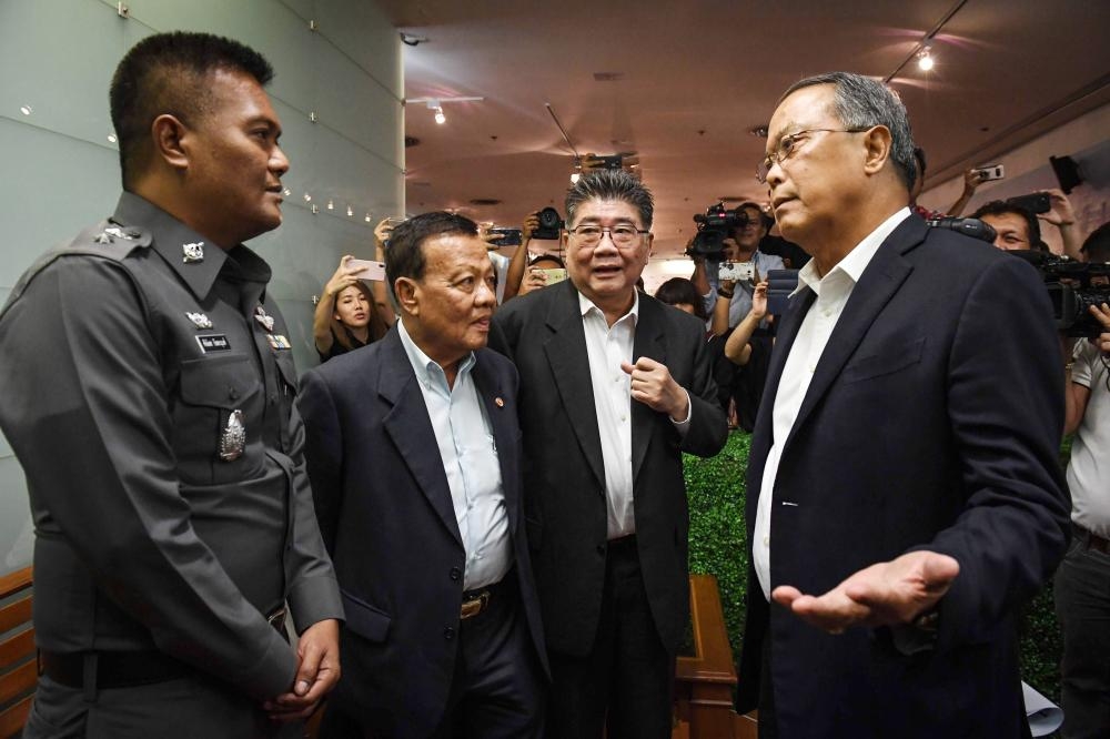 Pheu Thai party legal head Chusak Sirinul, right, speaks to a Thai police officer, left, during an attempt to stop the press conference as party officials look on at the party headquarters in Bangkok in this May 17, 2018 file photo. — AFP
