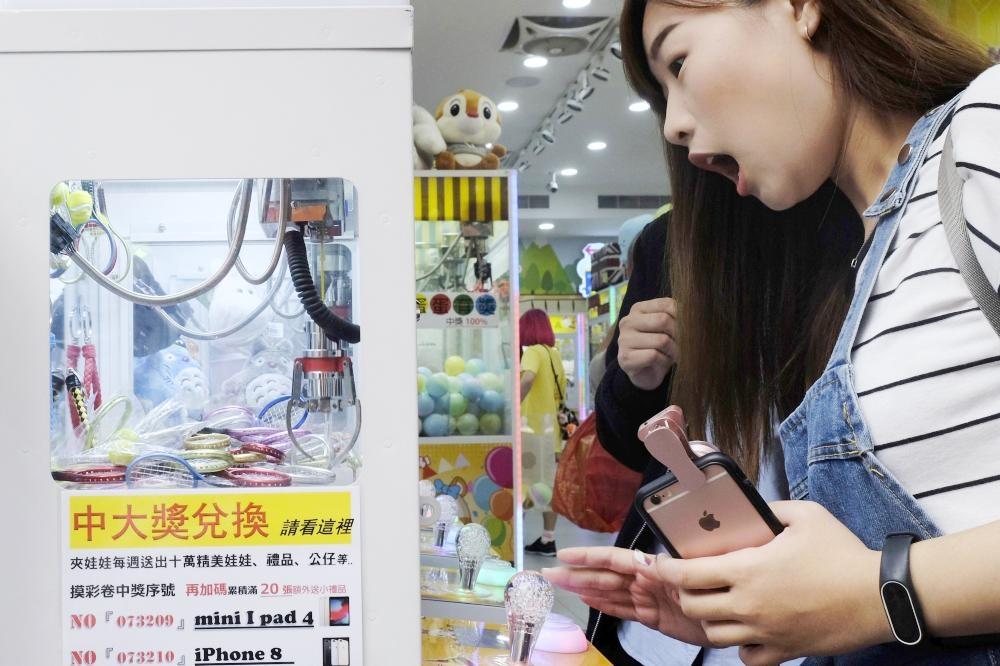 


A woman reacts while operating a claw crane machine at a store in Taipei in this Oct. 24, 2018 file photo. — AFP