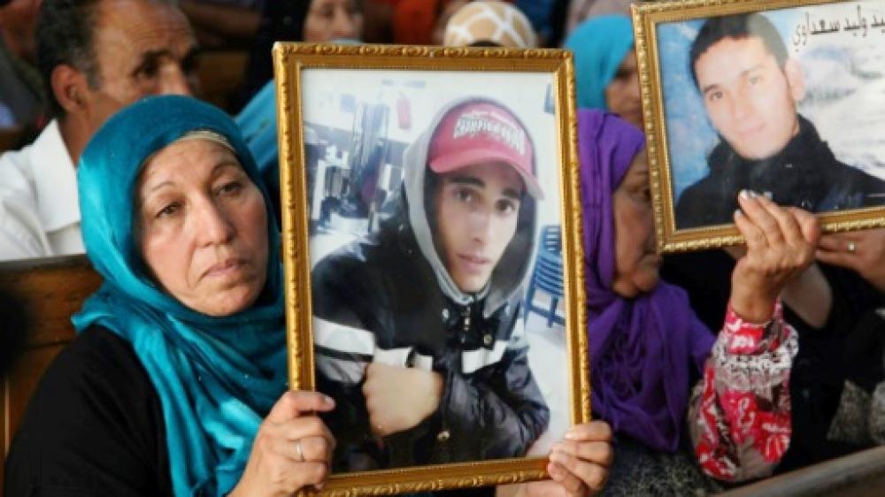 Families of victims of Tunisia's 2011 revolt against dictatorship carry portraits of their loved ones during a trial in Kasserine in this July photo. — AFP 