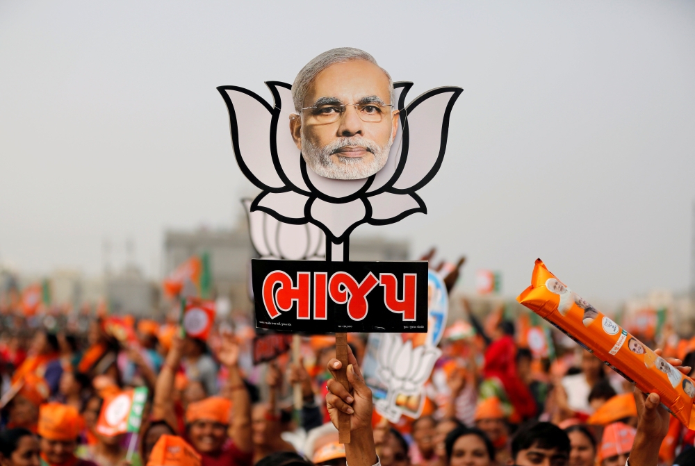  A supporter holds up a cut-out of a lotus, the election symbol of India’s ruling Bharatiya Janata party (BJP), with an image of Prime Minister Narendra Modi during a campaign meeting addressed by Modi ahead of Gujarat state assembly election in Kalol on the outskirts of Ahmedabad, India, in this Dec. 8, 2017 file photo. — Reuters