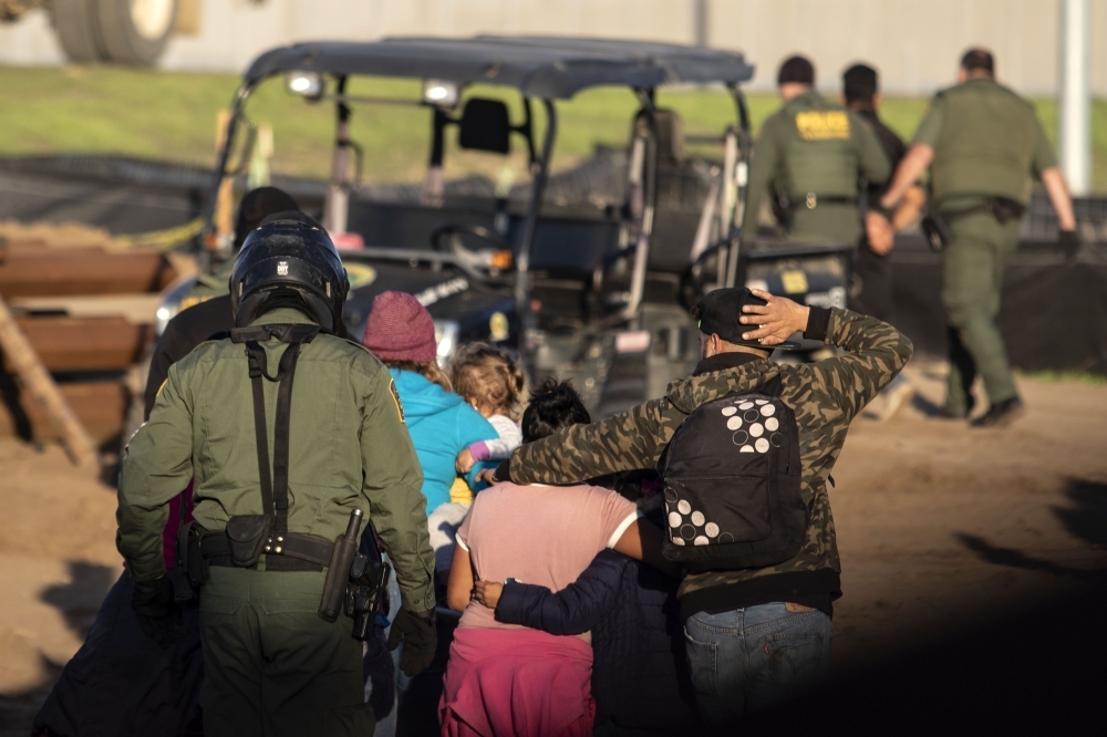 Central American migrants, traveling in a caravan, are taken into custody by US border patrol officers after crossing the Mexico-US border fence to San Diego County, as seen from Playas de Tijuana, Baja California state, Mexico, on Thursday. — AFP