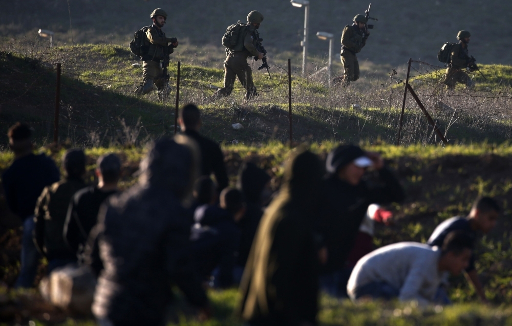 Israeli soldiers take position on a hillside facing Palestinian protesters during demonstrations near the Hawara checkpoint south of the occupied West Bank city of Nablus on Friday. — AFP