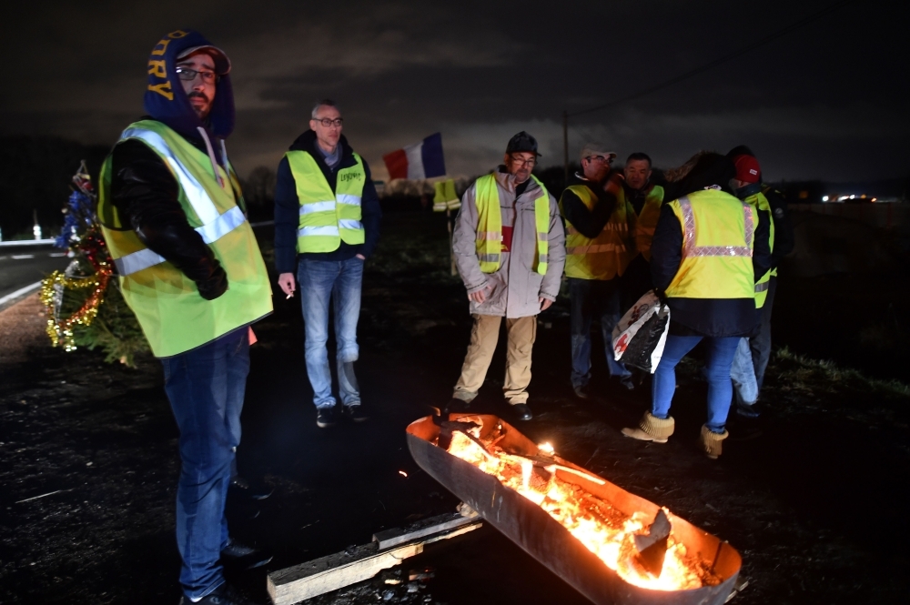 Yellow vests protestors stand by a fire next to a Christmas tree on the edge of one of the access roads to the South Le Mans ring road, France, on Sunday. — AFP