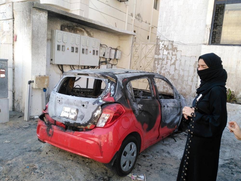 


Angry and frustrated, Nurhan Bassam stands beside her burned out car.