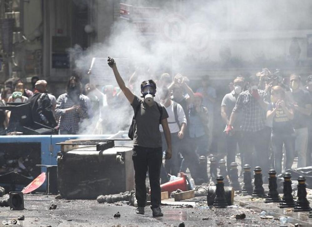 A Turkish protester wears a gas mask and holds a stone as demonstrators face riot police. — File photo