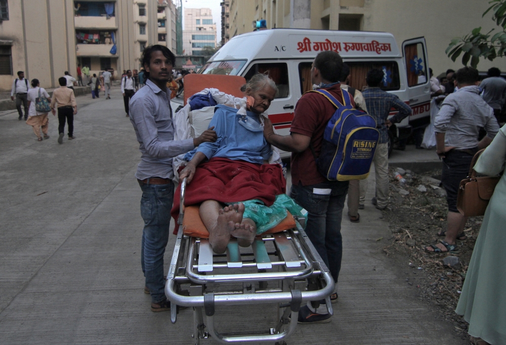 A woman sits in a stretcher after she was evacuated from a government hospital due to fire, on the suburbs of Mumbai, India, on Monday. — Reuters