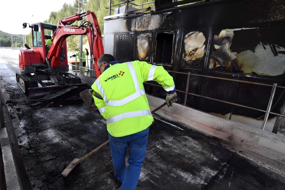 A worker of French construction group Vinci cleans near a damaged payment booth a day after the highway toll was set on fire in Bandol, near Marseille, southern France, following Yellow vests protests on Tuesday. — AFP