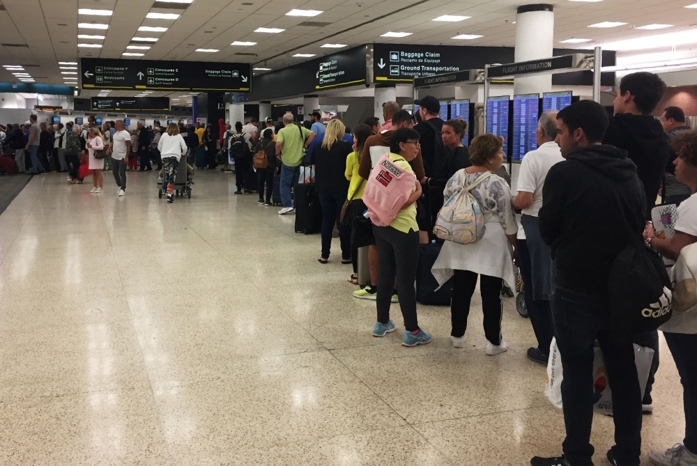Passengers flying from Miami International Airport wait in line to enter the checkpoint at Concourse F, where some of the flights of a closed terminal were diverted, in Miami, Florida, on Sunday. — AFP