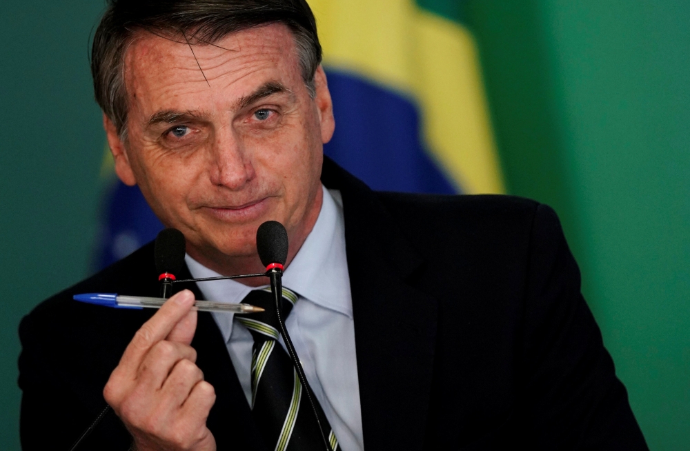 Brazil’s President Jair Bolsonaro shows a pen during a signing ceremony of the decree which eases gun restrictions in Brazil, at the Planalto Palace in Brasilia, Brazil, on Tuesday. — Reuters