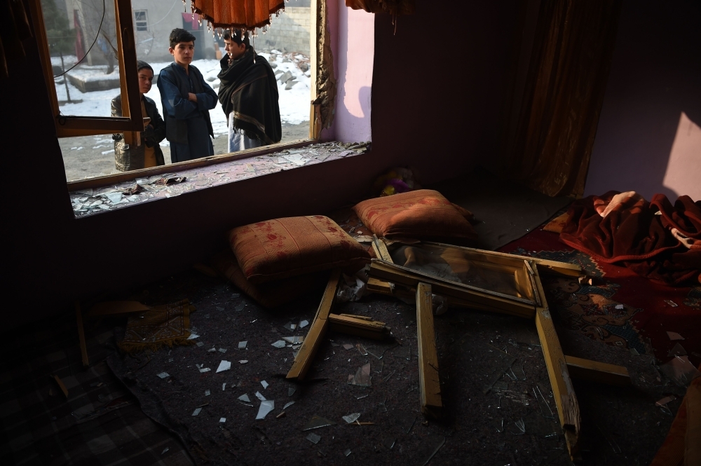 Afghan residents look through broken windows of a damaged shops near the site of a powerful truck bomb attack a day after it detonated near a foreign compound in Kabul on Tuesday. — AFP