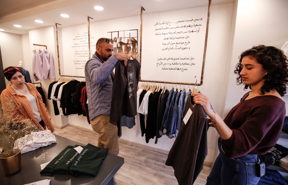 Palestinian fashion designer Yasmeen Mjalli (right) arranges clothes in her shop where her label collection 