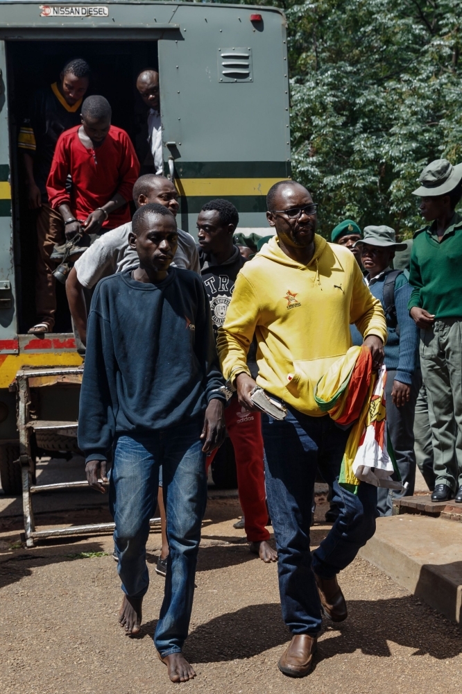 Zimbabwean cleric and activist Pastor Evan Mawarire (right) exits a prison truck as he arrives at the Harare Magistrates Court in Harare on Saturday, for a court hearing on subversion charges. — AFP