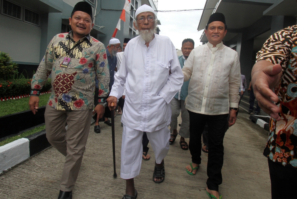 Abu Bakar Bashir (cener), the alleged mastermind of the 2002 Bali bombings, walks as he is visited by Yusril Ihza Mahendra (right), who is the lawyer of Indonesia's presidential candidate Joko Widodo, at Gunung Sindur prison in Bogor, Indonesia, Friday. — Reuters