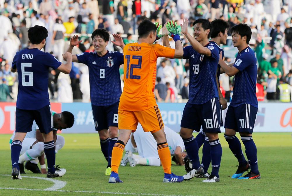 Japan’s players celebrate at the end of the AFC Asian Cup match against Saudi Arabia at Sharjah Stadium Monday. — Reuters