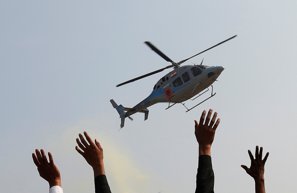Supporters wave toward a helicopter carrying Keshav Prasad Maurya, the Uttar Pradesh state’s president for the ruling Bharatiya Janata Party (BJP), during an election campaign rally in Bah, in the central state of Uttar Pradesh, India, in this Feb. 2, 2017 file photo. — Reuters