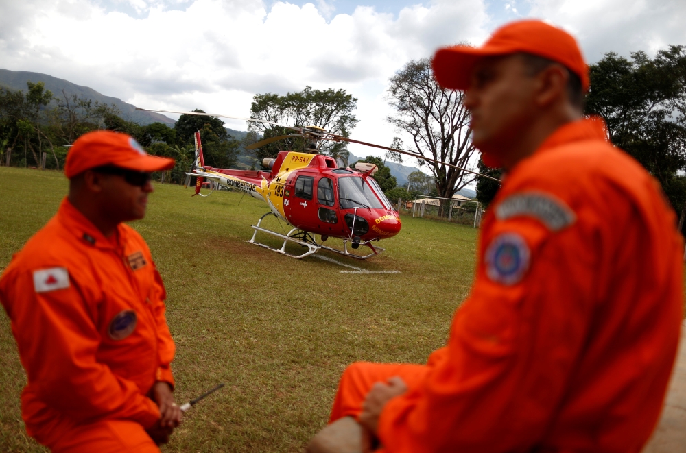 Fire department pilots talk next to a helicopter before flying to rescue victims of a collapsed tailings dam owned by Brazilian mining company Vale SA, in Brumadinho, Brazil, on Tuesday. — Reuters