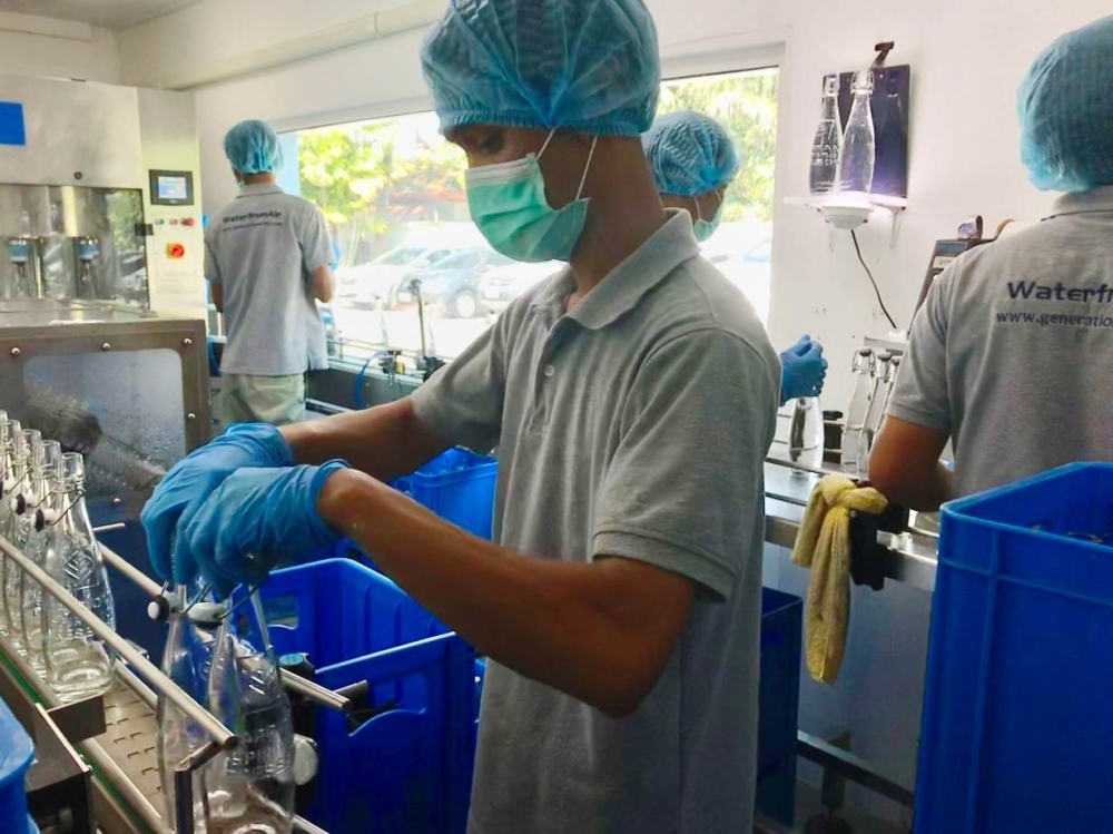 Operators work to clean and fill glass bottles at Generation Water's pilot plant, which produces 