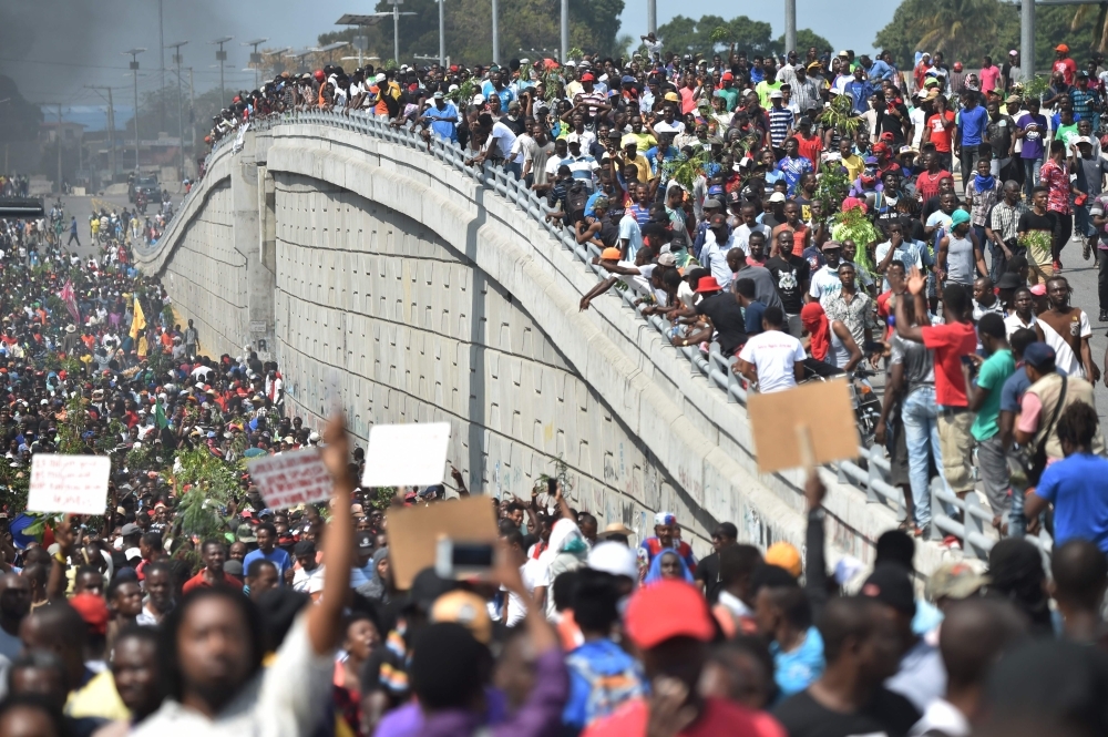 Demonstrators march through the streets of Port-au-Prince, on Thursday. Demonstrators demanded the resignation of Haitian President Jovenel Moise, as protesters blocked streets and lit tires during their march in the Haitian capital. — AFP