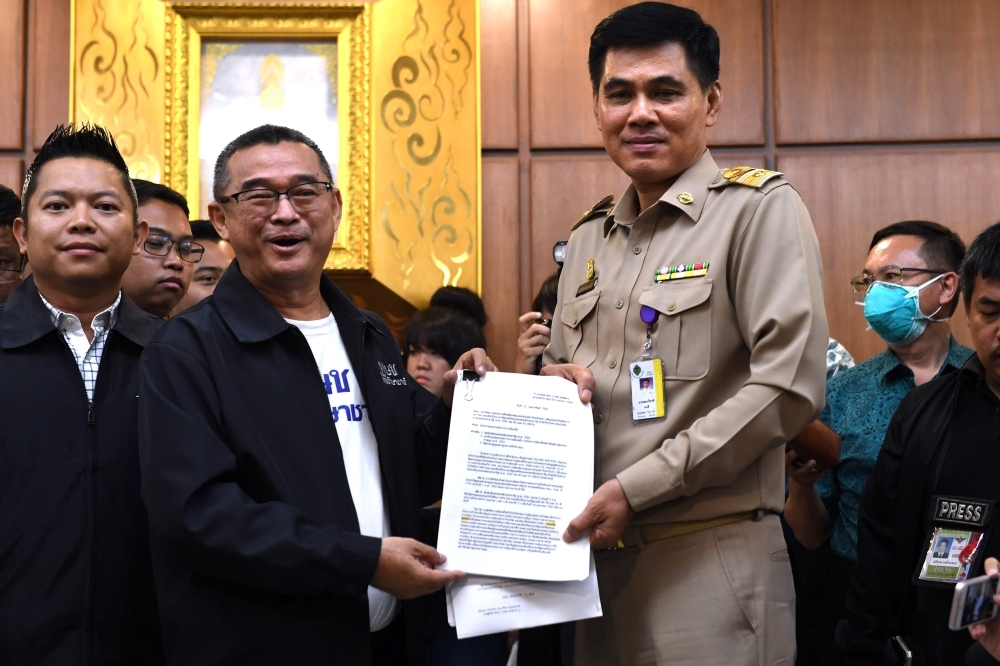 Ruengkrai Leekitwatana, left, an official of Pheu Thai party submits a petition to the election commission in Bangkok on Monday to investigate junta leader Prayut Chan-O-Cha’s qualification as candidate for prime minister. — AFP