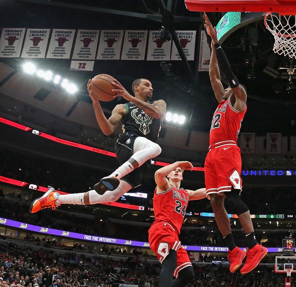 George Hill of the Milwaukee Bucks leaps to pass around Kris Dunn (R) of the Chicago Bulls at the United Center in Chicago Monday. — AFP 
