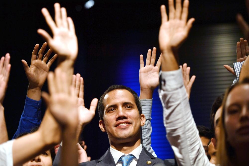 


Venezuelan National Assembly head and self-proclaimed acting president Juan Guaido, center, raises his hands surrounded by students after speaking at the Metropolitan University in Caracas on Monday. — AFP