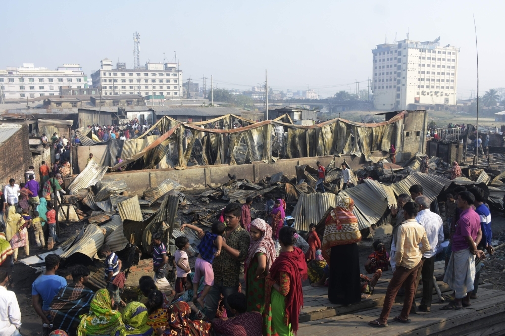 Residents walk past their destroyed houses after a fire broke out in Chittagong on Sunday. — AFP
