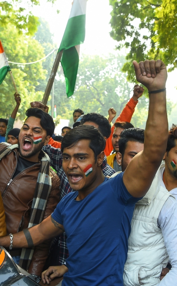 An injured man that an angry mob had attacked, believing him to be a Kashmiri who had shouted pro-Pakistan slogans, is shielded by policemen in New Delhi on Sunday.  