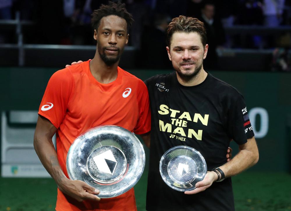 France's Gael Monfils celebrates winning the Rotterdam Open with the trophy alongside runner-up Switzerland's Stan Wawrinka Sunday. — Reuters