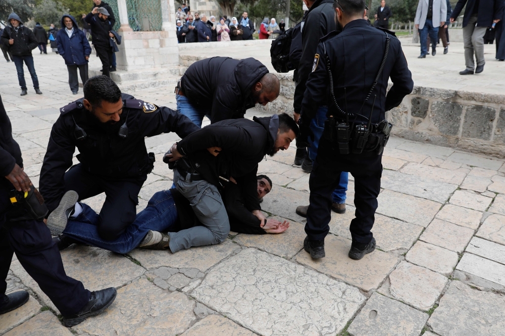 


Israeli policemen detain a Palestinian demonstrator during clashes, after protesters tried to break the lock on a gate at the Al-Aqsa Mosque compound in Jerusalem’s Old City on Monday after it was closed by Israeli police. — AFP
