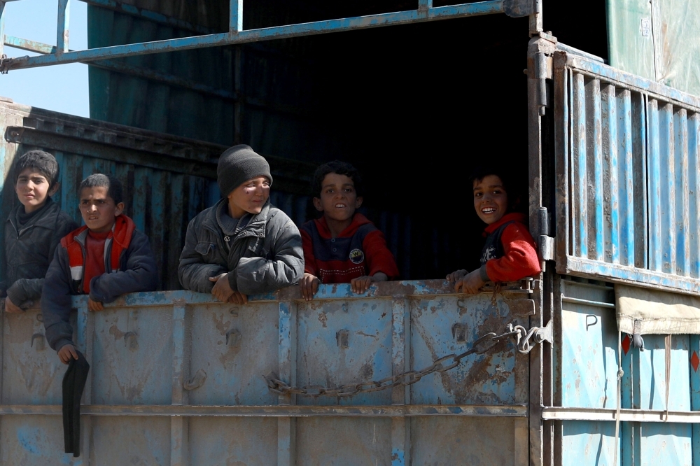 A fighter from the Syrian Democratic Forces (SDF) gives bread to children near the village of Baghouz, Deir Al Zor province, Syria, on Wednesday. — Reuters