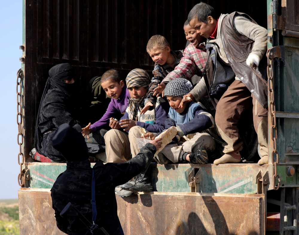 A fighter from the Syrian Democratic Forces (SDF) gives bread to children near the village of Baghouz, Deir Al Zor province, Syria, on Wednesday. — Reuters