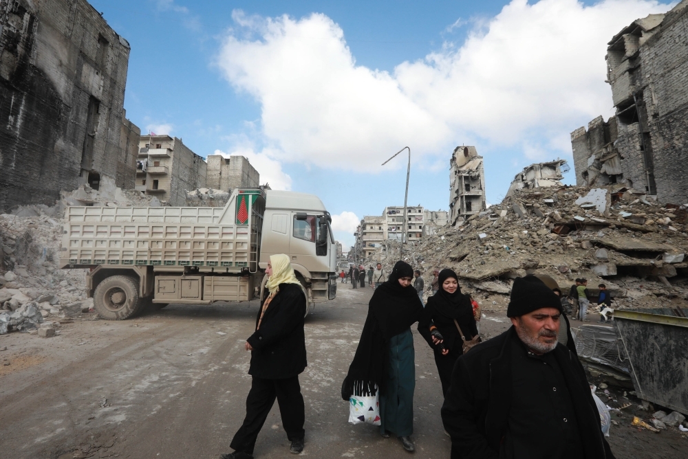 Syrians walk past a truck removing the rubble from a building that was destroyed during battles between rebel fighters and regime forces, in the former opposition held district of Salaheddin in the northern Syrian city of Aleppo, in this Feb. 11, 2019 file photo. — AFP