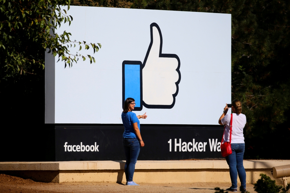 File photo shows two women taking photos in front of the entrance sign to Facebook headquarters in Menlo Park, California. — Reuters