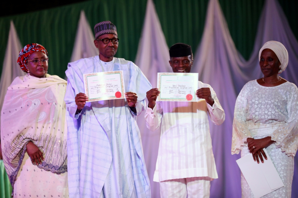 Nigeria’s President Muhammadu Buhari poses with Vice President Yemi Osinbajo while holding his certificate after collecting it from the electoral commission following the poll win in Abuja, Nigeria, on Wednesday. — Reuters