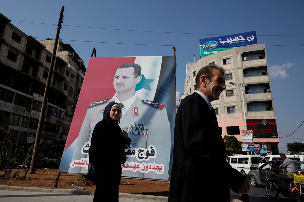 People walk in front of a billboard with a picture of Syrian President Bashar Assad in Homs, Syria, in this Sept. 18, 2018 file photo. — Reuters