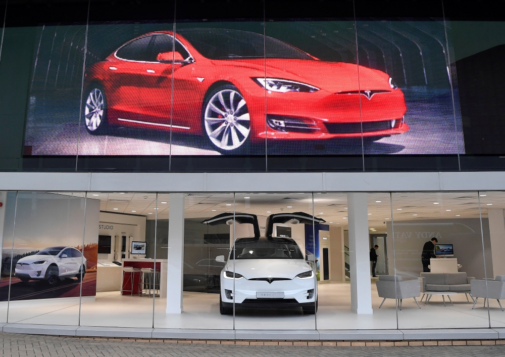 Employees work in a Tesla showroom, as Tesla announces it would close many stores and its sales would now be online-only around the world, in west London, Britain, Friday. — Reuters