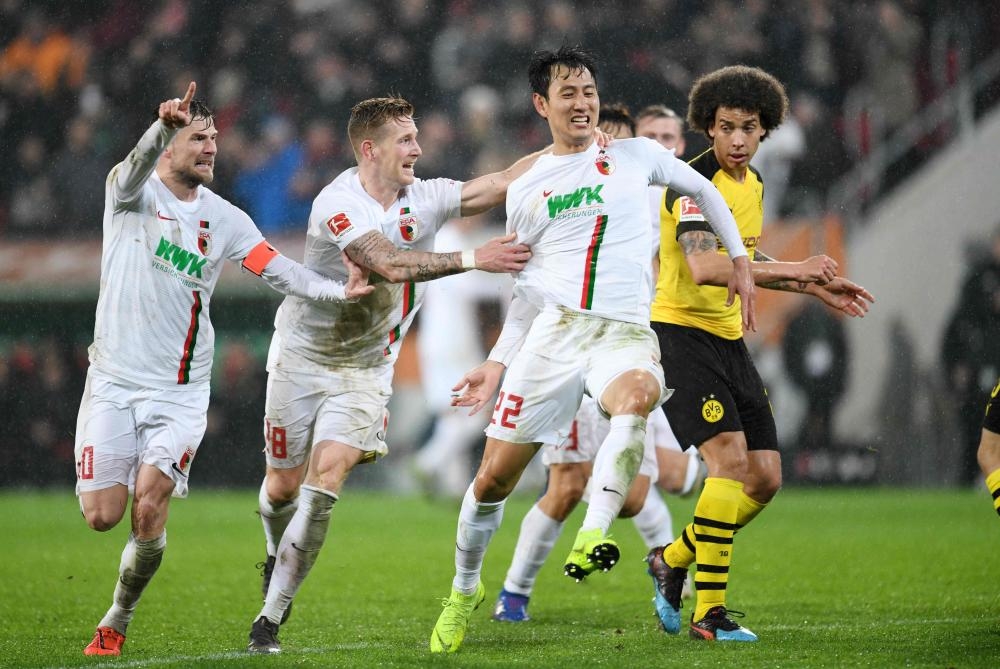(L-R) Augsburg’s midfielder Daniel Baier, forward Andre Hahn and Dong-won Ji celebrate aftr scoring against Borussia Dortmund during the German first division match in Augsburg Friday. — AFP 