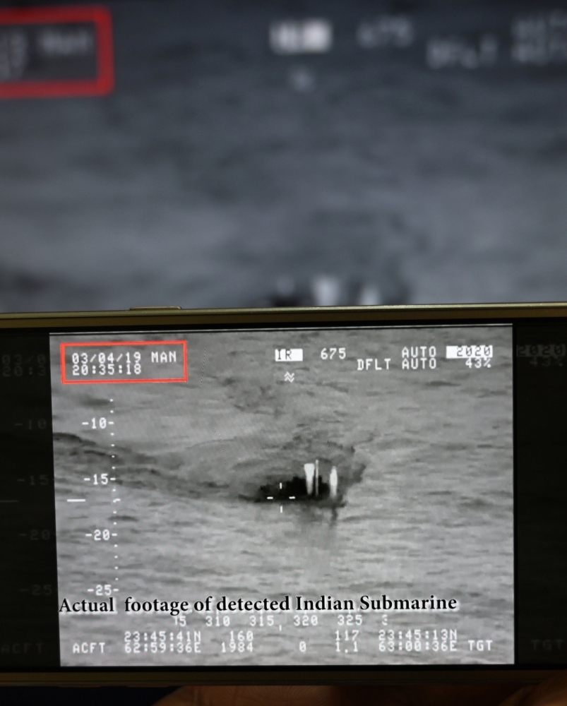 A Pakistani journalist watches a video released by Pakistan’s Navy that allegedly shows an Indian submarine, on a smartphone in Islamabad on Tuesday. — AFP