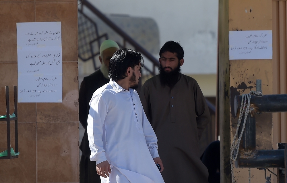 A Pakistani worker, second right, of banned militant Jamaat-ud-Dawa (JuD) — an organization believed by the United Nations (UN) to be a front for the banned militant group Lashkar-e-Taiba — stands at the main entrance of a mosque belonging to the (JuD) in Islamabad on Wednesday. — AFP