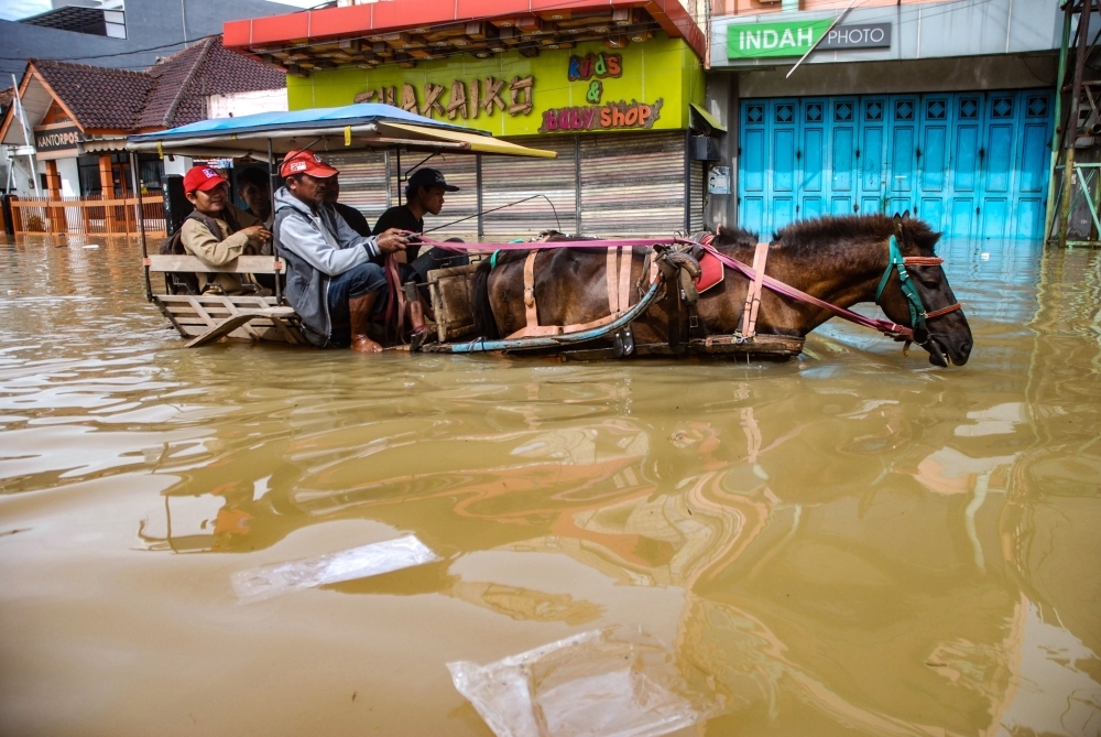 Residents commute along a flooded road in Dayeuhkolot village in Bandung, West Java province, Indonesia, in this in this unrelated photo taken March 7, 2019. — AFP