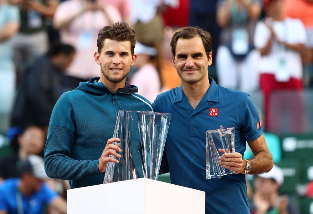 Dominic Thiem (L) of Austria holds the championship trophy after beating Roger Federer (R) of Switzerland at the BNP Paribas Open final in Indian Wells, California, Sunday. — AFP