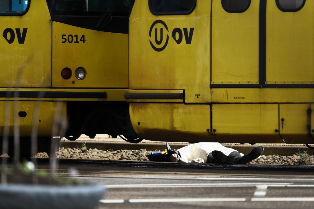 A body lying on the ground is covered near a tram at the 24 Oktoberplace in Utrecht Monday where a shooting took place. — AFP