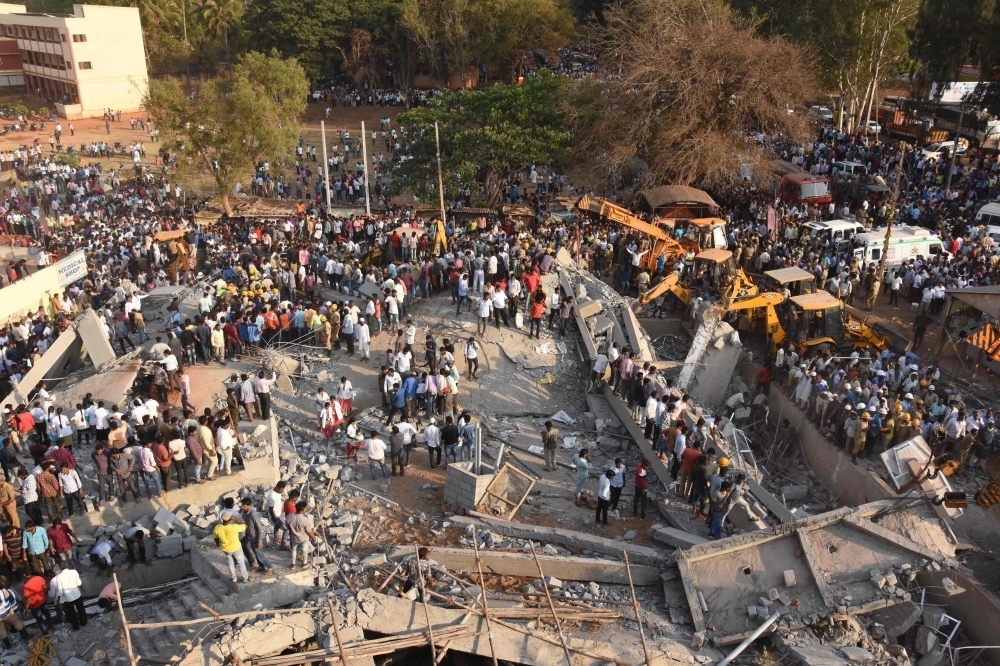 Onlookers gather near the rubble while rescue teams search for survivors after an under-construction multi-story building collapsed in Dharwad district of Karnataka on Tuesday. — AFP