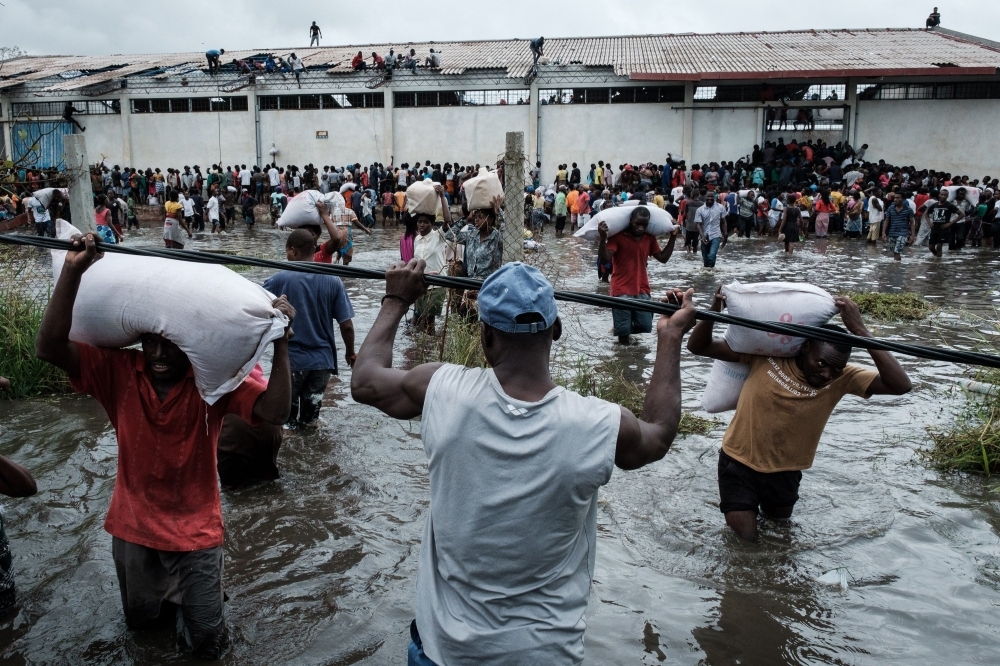 People take part in the looting sacks of Chinese rice printed “China Aid” from a warehouse which is surrounded by water after cyclone hit in Beira, Mozambique, on Wednesday. — AFP