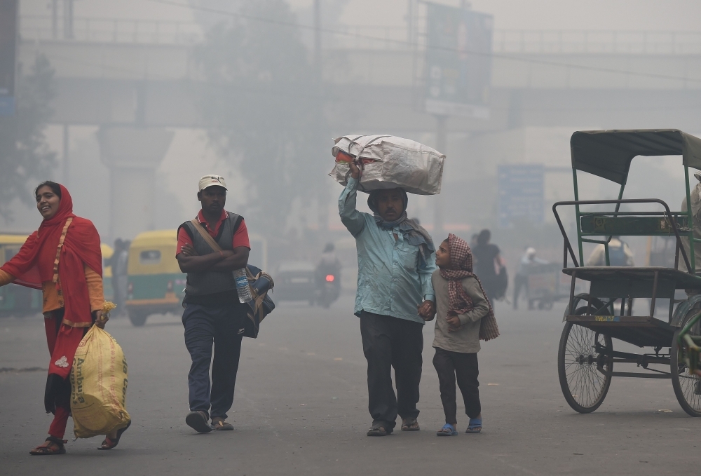 A family carries belongings while looking for a rickshaw amid heavy smog in New Delhi in this Nov. 5, 2018 file photo. — AFP