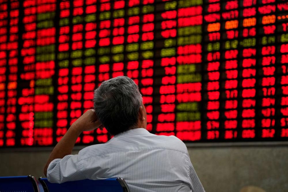 An investor looks at an electronic board showing stock information at a brokerage house in Shanghai, China, in this file photo. — Reuters